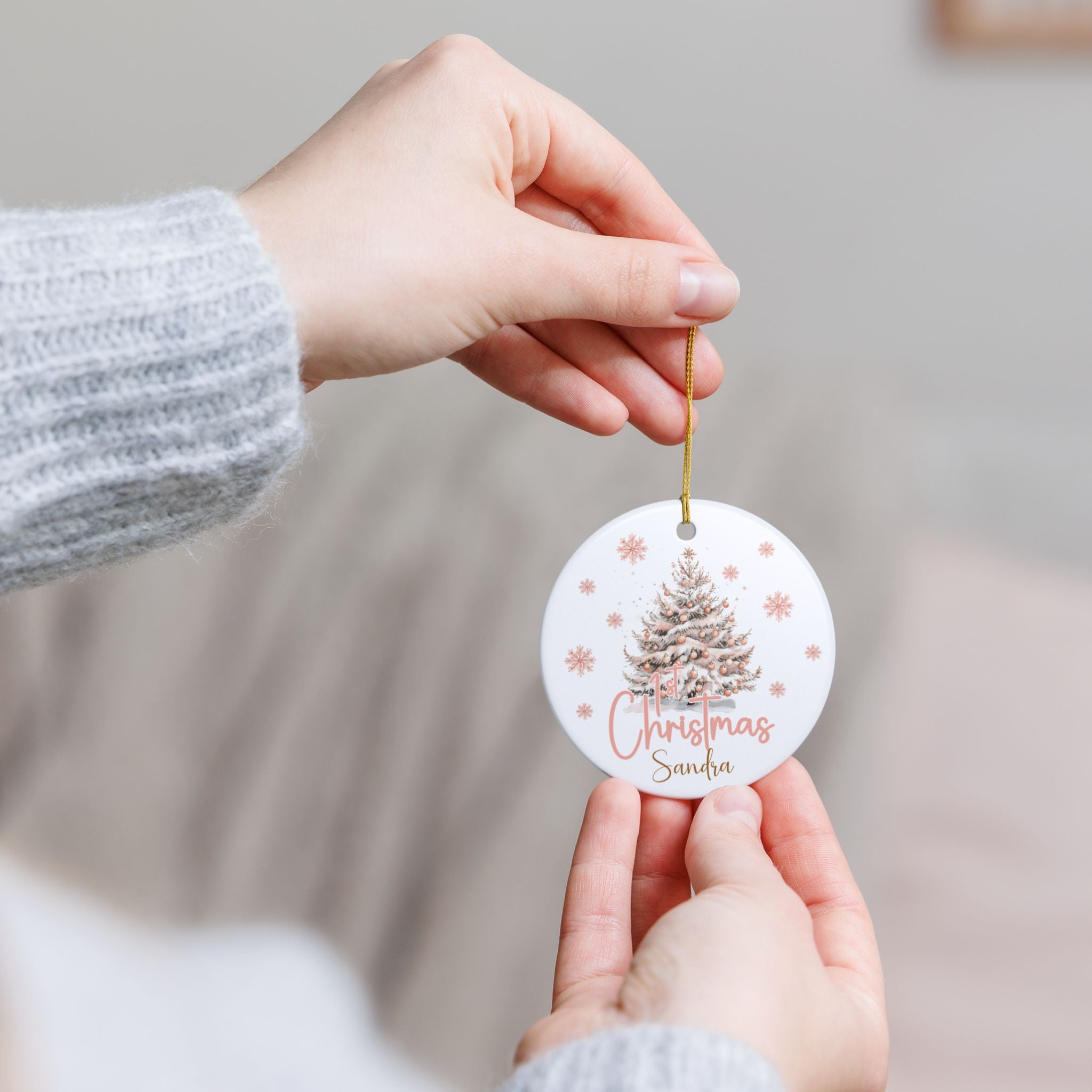 Hand holding a Christmas ornament with a tree design and 'Christmas Sandra' text.