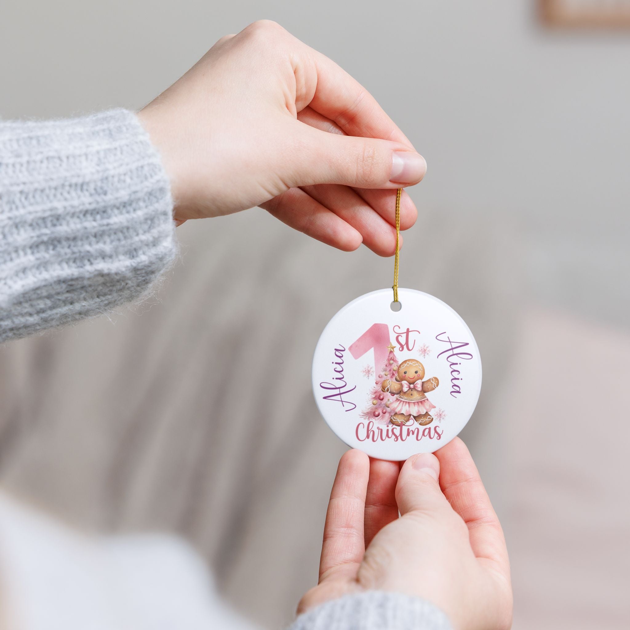 Hand holding a personalized Christmas ornament with a baby design and text.