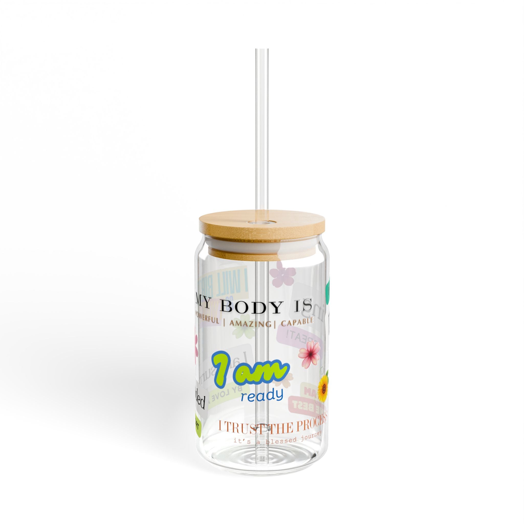 Clear tumbler with bamboo lid and straw featuring motivational text and floral designs on a white background.