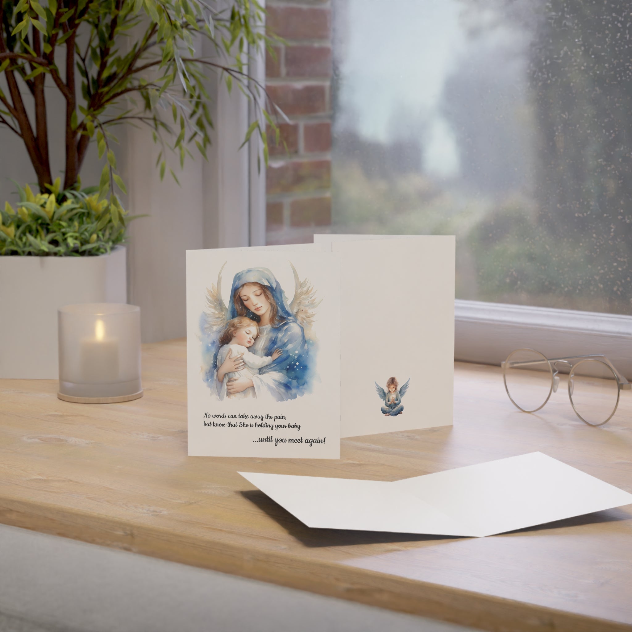 Greeting card with religious illustration for condolences of miscarriage, still birth, baby loss on a wooden surface with a candle and glasses.