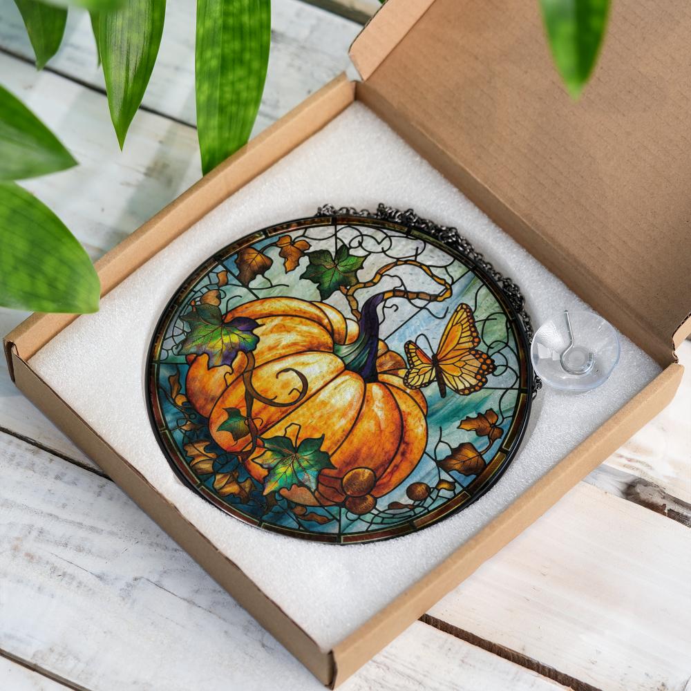 Stained glass panel with pumpkin and butterfly design in a box on a wooden surface