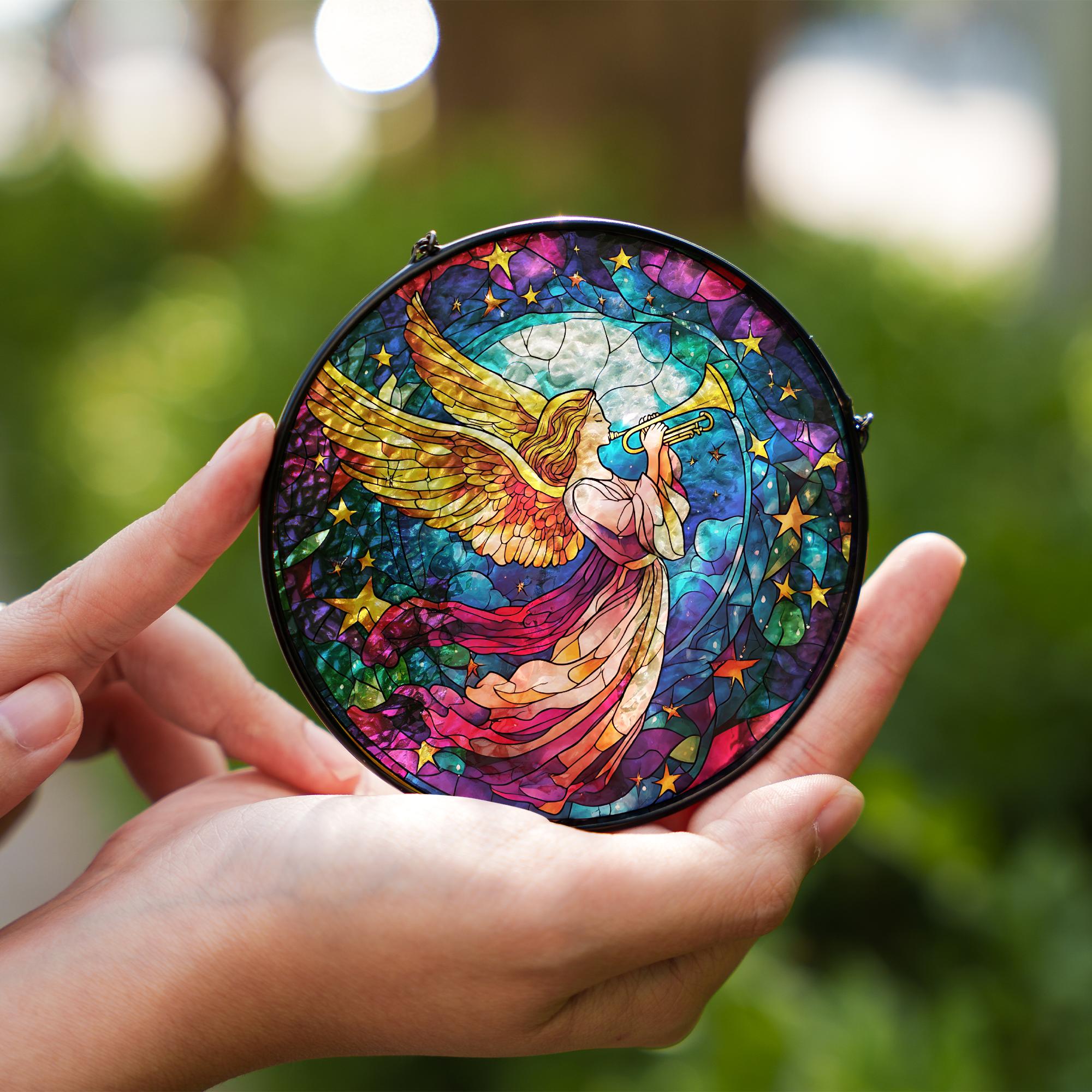 Colorful stained glass angel with a trumpet held in hands against a blurred green background
