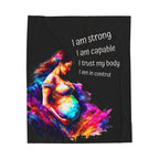 A colorful blanket with a pregnant woman's figure and the text 'I am strong, I am capable, I trust my body, I am in control' printed on it.