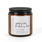 Candle jar with a black lid and white label on a white background - smells like the doula is here