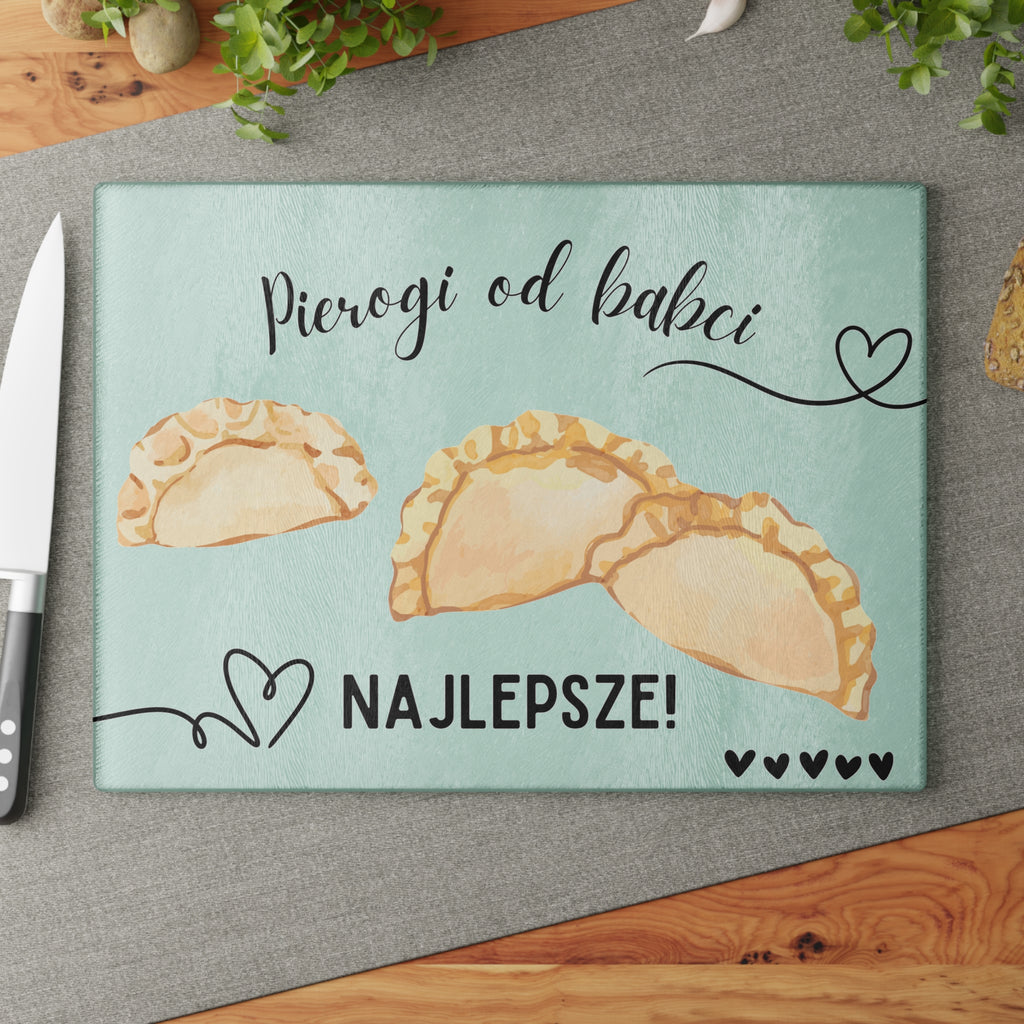 Glass cutting board with pierogi design and text on a white brick wall background