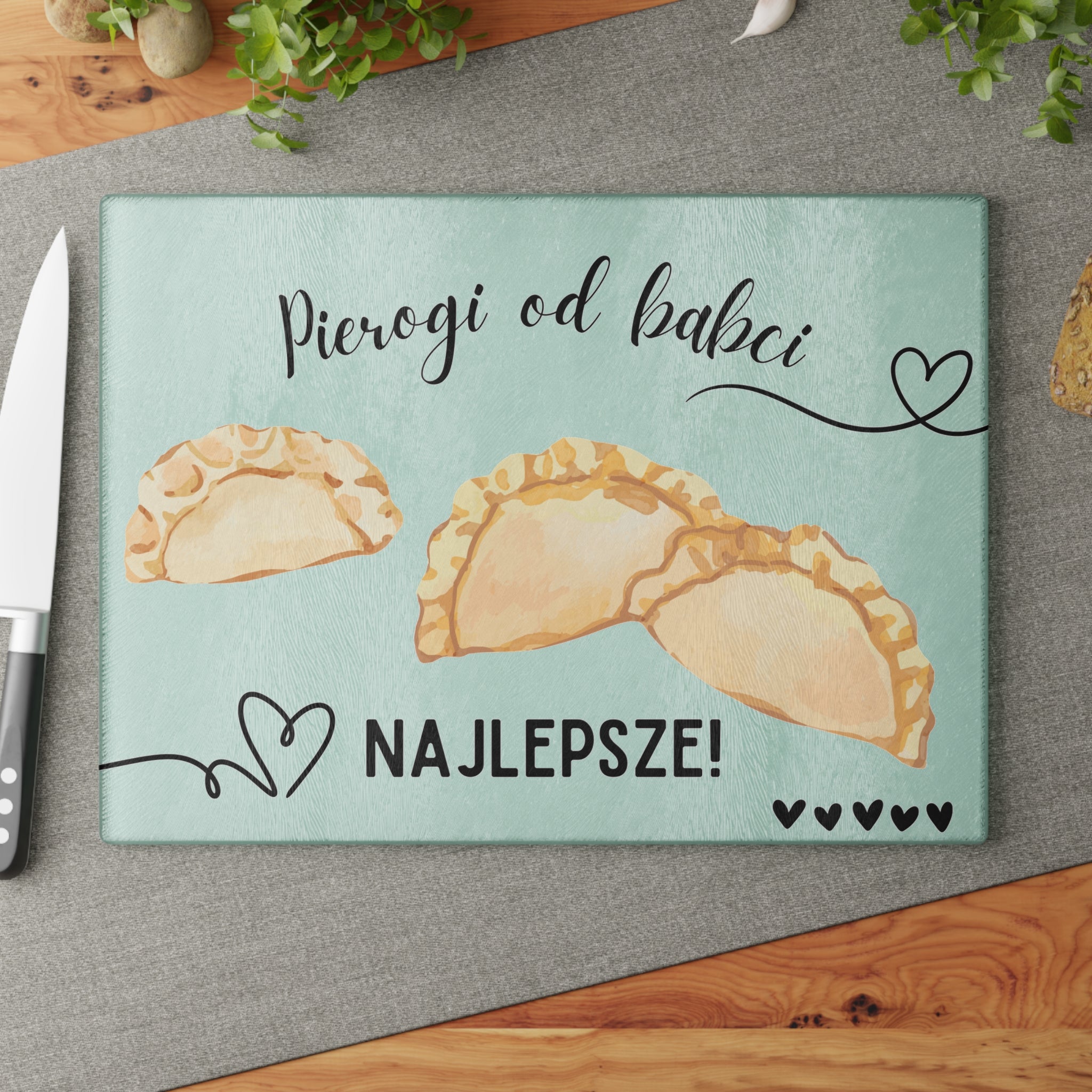 Glass cutting board with pierogi design and text on a white brick wall background