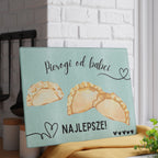 Glass cutting board with pierogi design and text on a white brick wall background