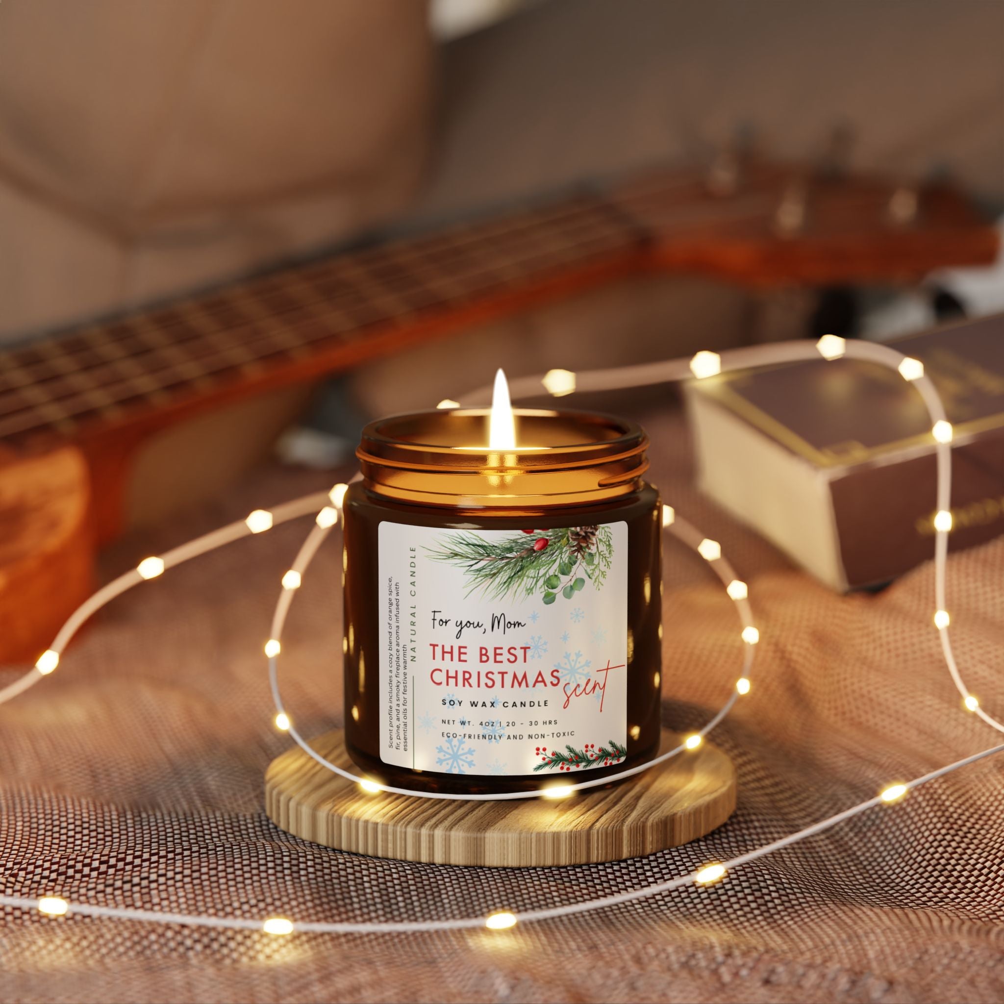 Candle in a jar labeled 'The Best Christmas Scent' on a wooden surface with string lights and a guitar in the background.