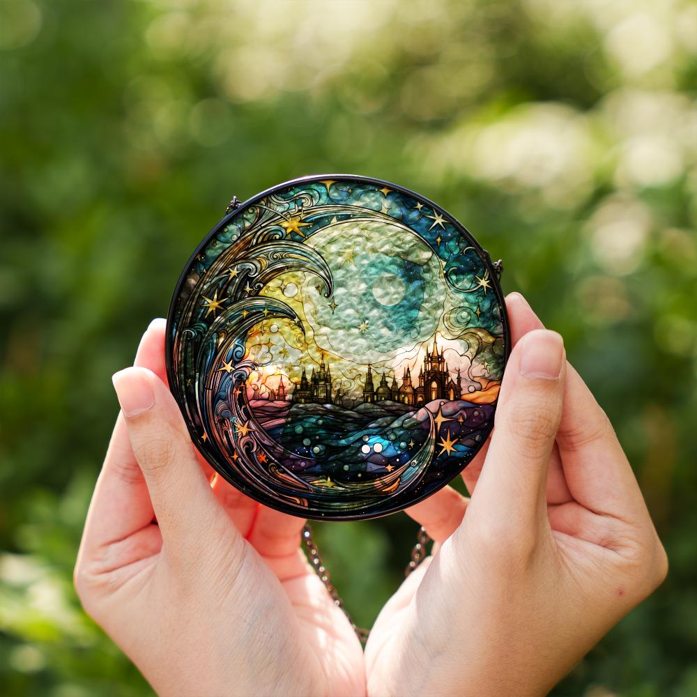 Person holding a round, intricately designed stained glass suncatcher against a blurred green background