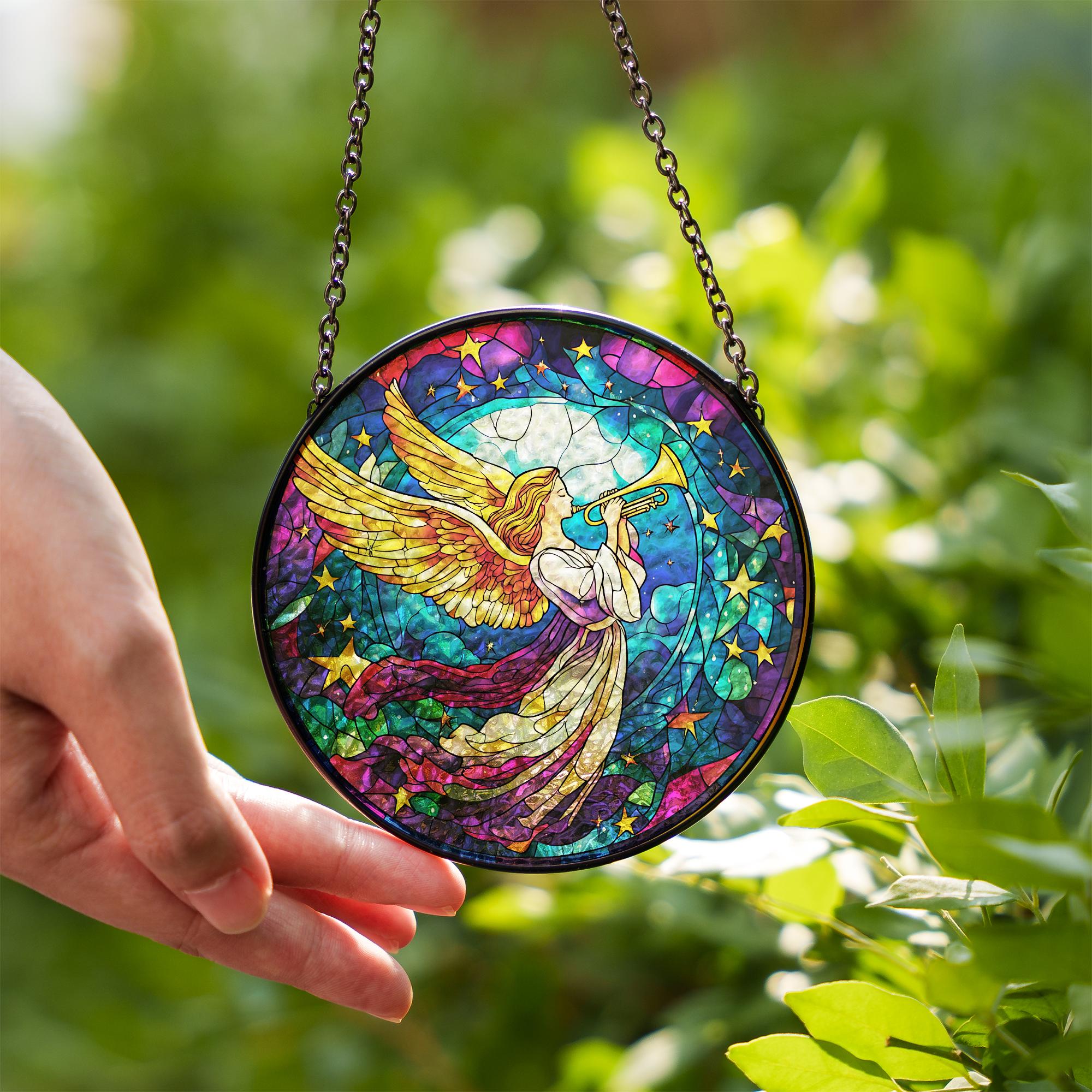 Colorful stained glass angel panel held by a hand with a green leafy background