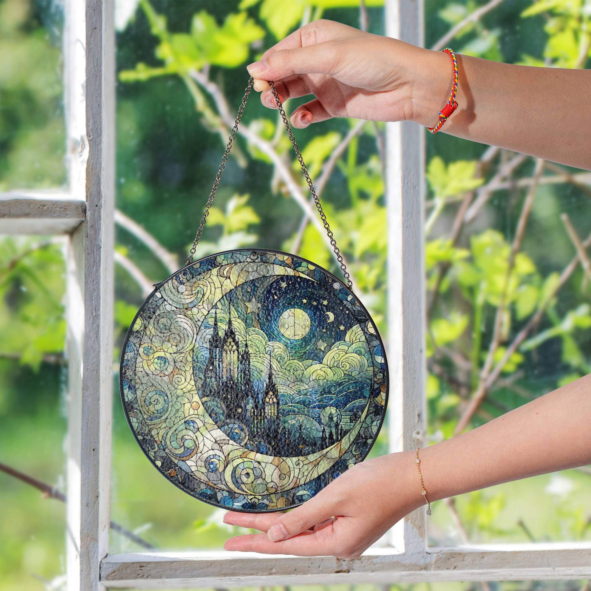 Gothic cathedral stained glass suncatcher featuring a crescent moon and starry night sky, hanging on a black chain with sunlight illuminating the colors