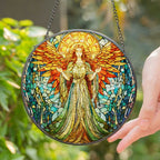 Stained glass angel panel held by a hand with a blurred green background