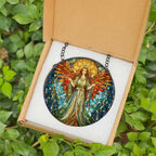 Stained glass angel suncatcher with vibrant red, blue, and gold tones, displayed in a gift box with black metal chain, set against a green leafy background