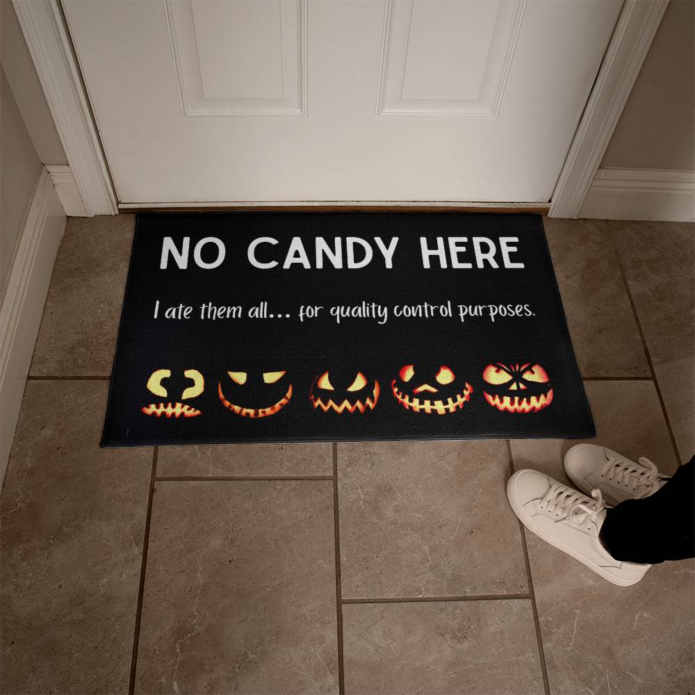 Halloween doormat with jack-o'-lanterns and text 'No Candy Here' on a tiled floor.