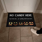 Halloween doormat with jack-o'-lanterns and text 'No Candy Here' on a tiled floor.