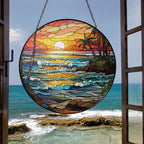 Stained glass suncatcher featuring a vibrant beach sunset with ocean waves and warm colors, hanging in a window and glowing in natural sunlight.